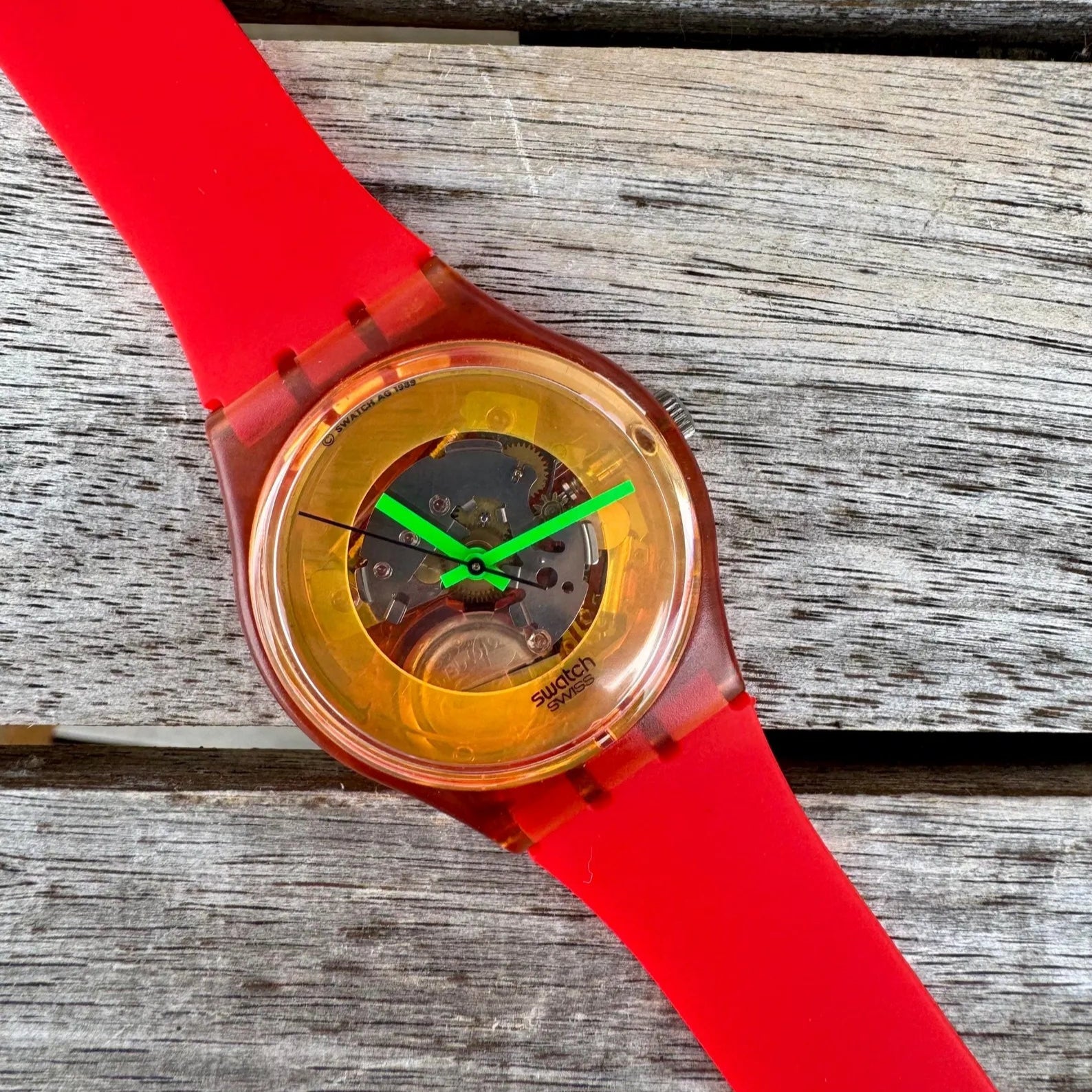 Watch with a red strap and transparent case on a wooden surface