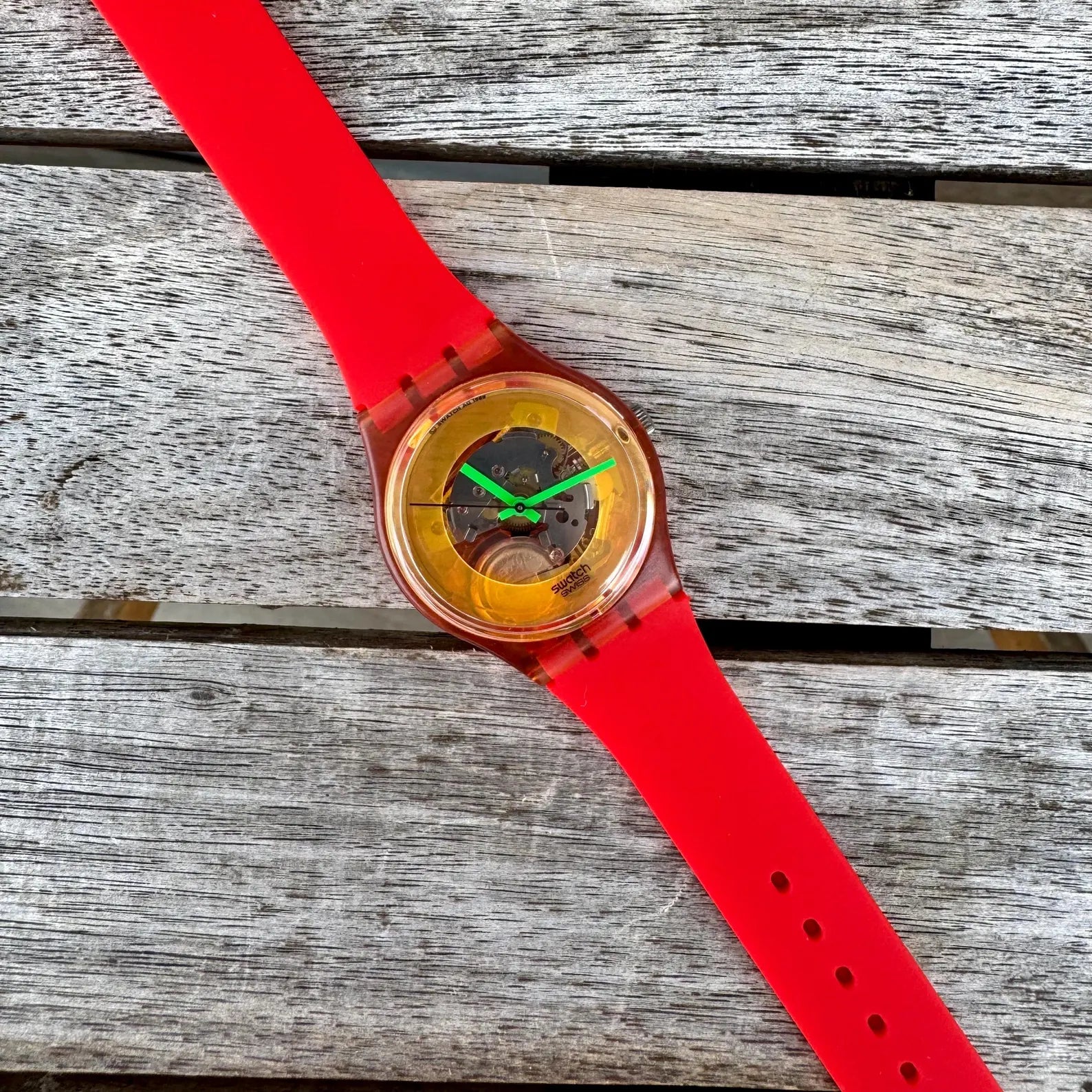 Watch with a red strap on a wooden surface