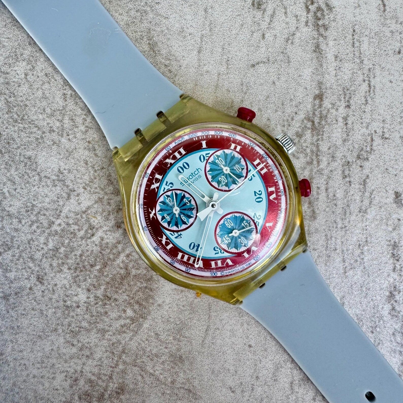 Swatch Wristwatch with a red and blue face on a textured surface